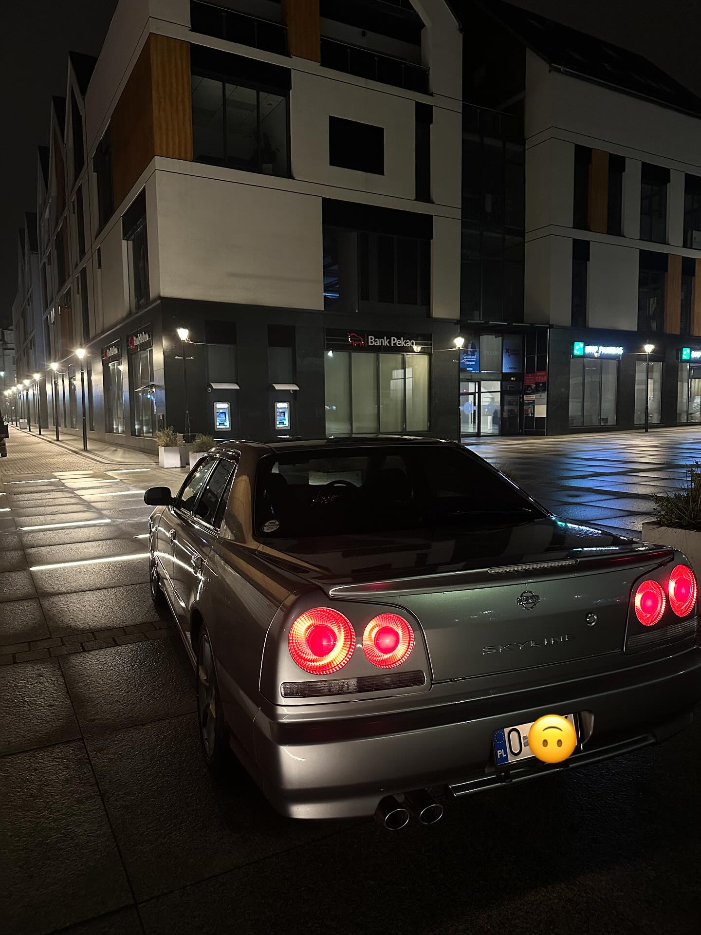 Srebrny Nissan Skyline R34 sedan nocą